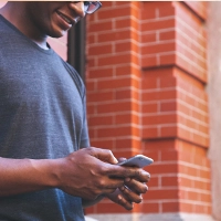 A man holding a mobile phone outside a brick building